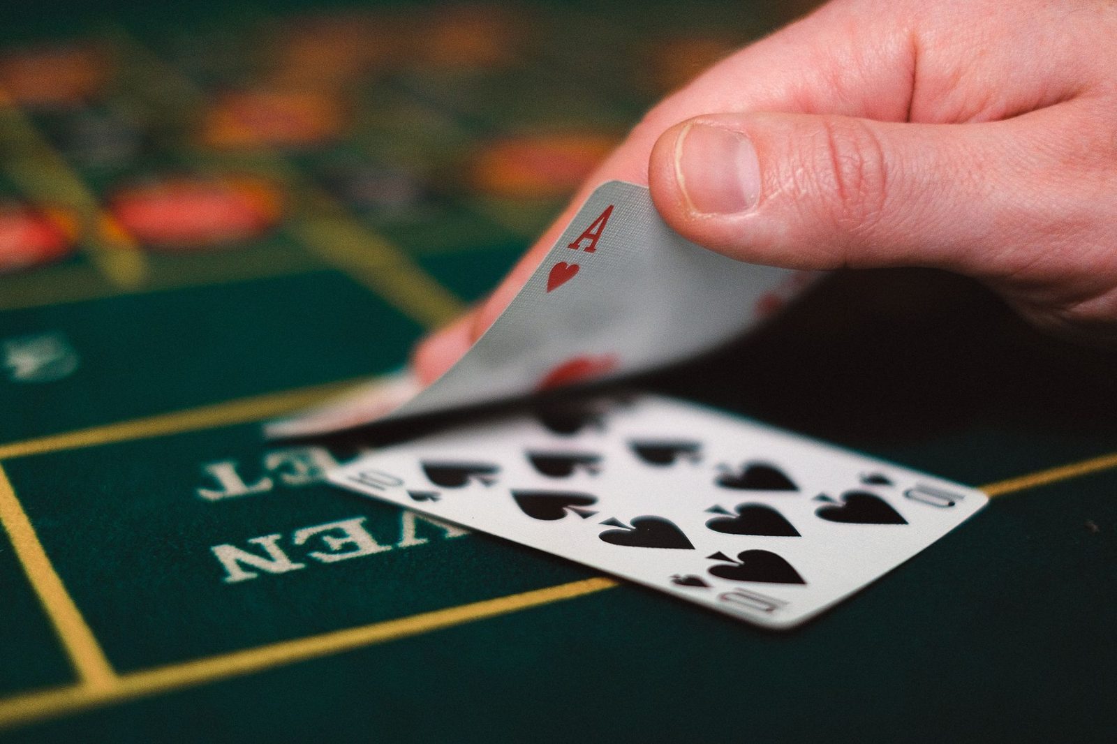 Hand with an ace of hearts on green felt